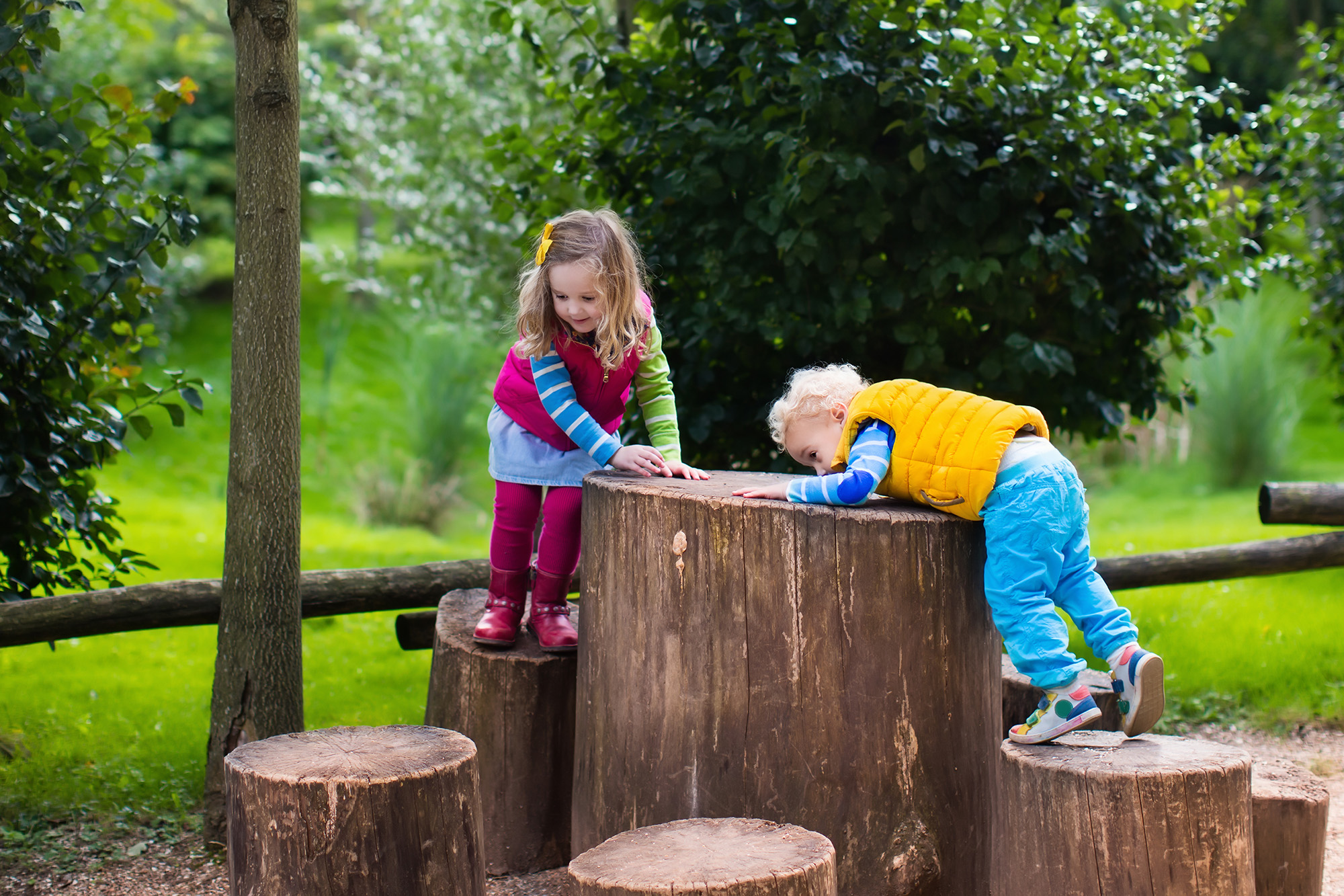 two kids climbing repurposed stump