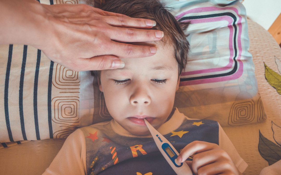 Child lying in bed with thermometer in mouth